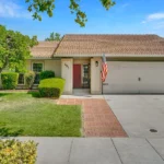 Real estate house with a red door, two-car garage, and American flag.