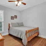 Bedroom with light gray walls with a wooden bed with gray bedding.