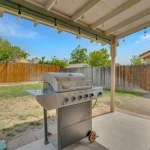 A gas grill under a covered patio with string lights