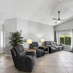 Living room with gray walls, tiled flooring and black reclining sofa