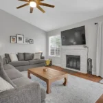 living room with gray sofa, wooden coffee table and brick fireplace