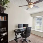 home office with brown carpet features a black desk and dual monitors