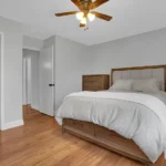 bedroom with a wooden floor, gray walls, and a ceiling fan.