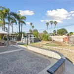 backyard in California with palm trees, a stone patio, and a gazebo with chairs
