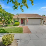 Real estate house with a red-tiled roof, American flag, and a two-car garage.
