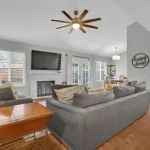Living room with gray sofas, a ceiling fan, and a wall-mounted TV