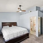 bedroom with a dark wood bed, white bedding, and beige carpet.